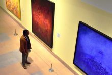 One person standing in front of three paintings on a wall