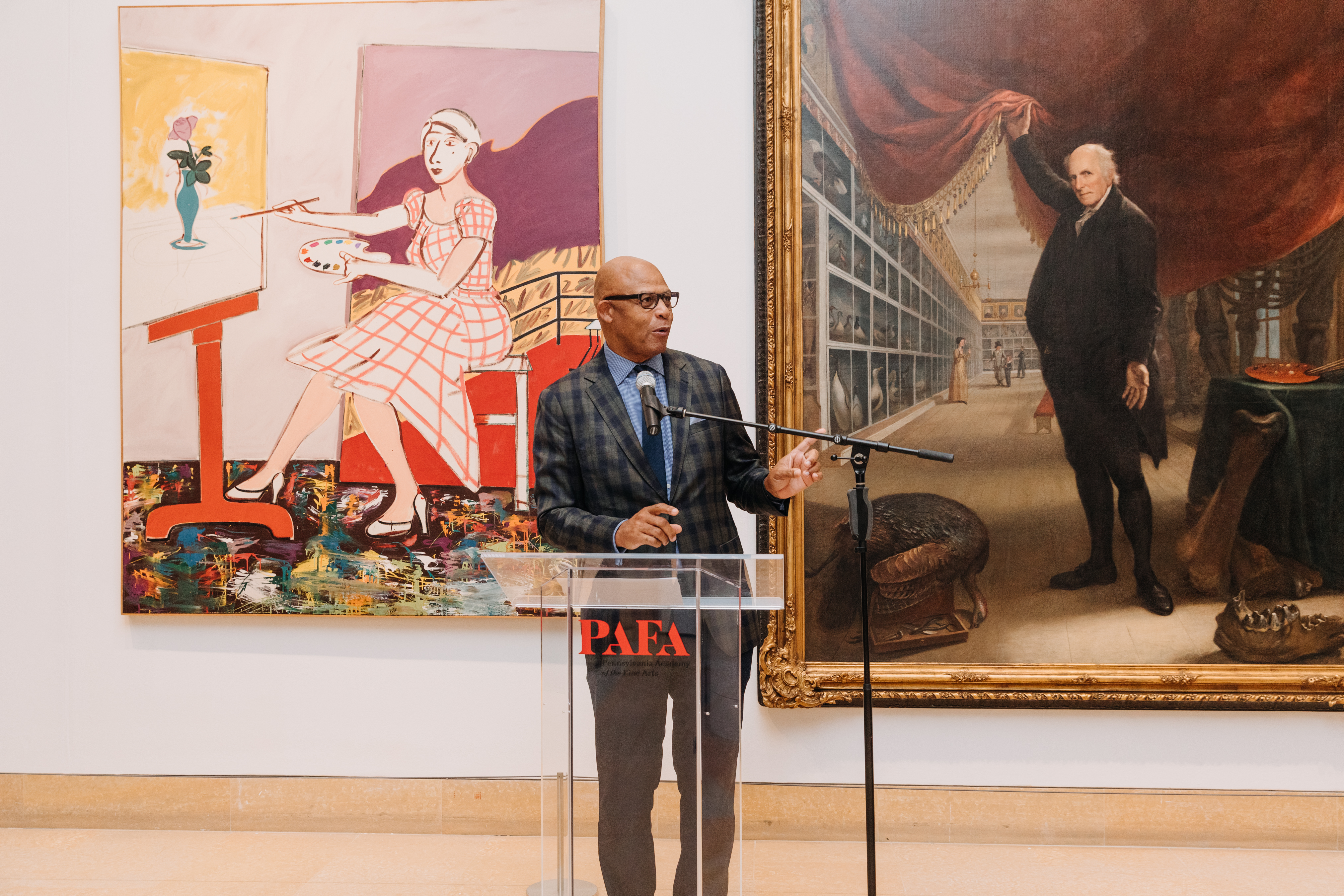 Eric standing at a podium in front of paintings.