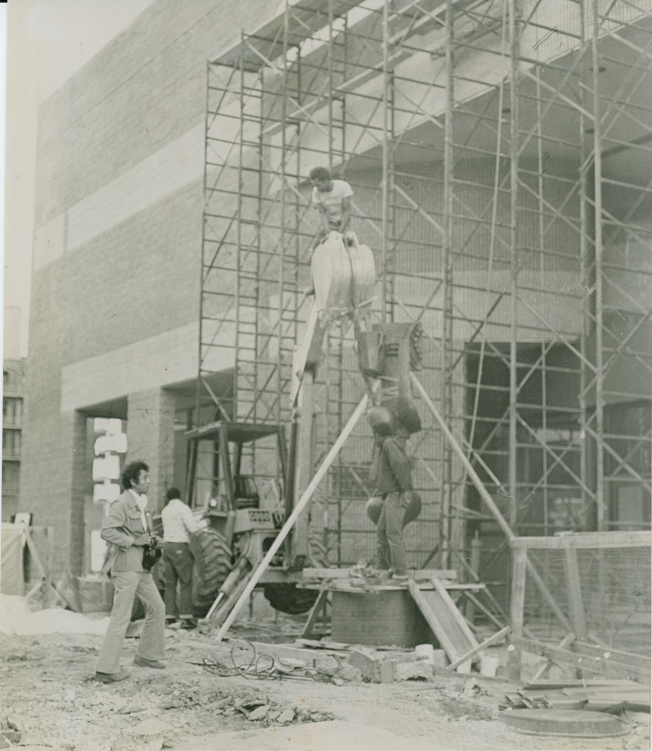 Black and white photo of people installing an outdoor sculpture.