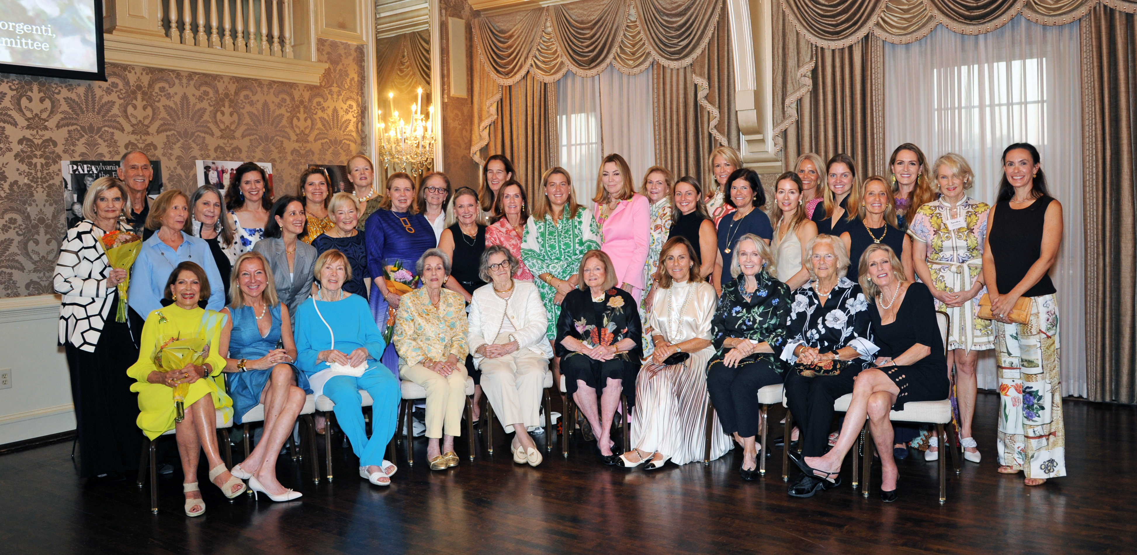 Group photo taken during the Women’s Committee 75th Anniversary Diamond Jubilee, featuring honorees and Women’s Committee members from past, present, and future generations, seated and standing in an elegant event setting.