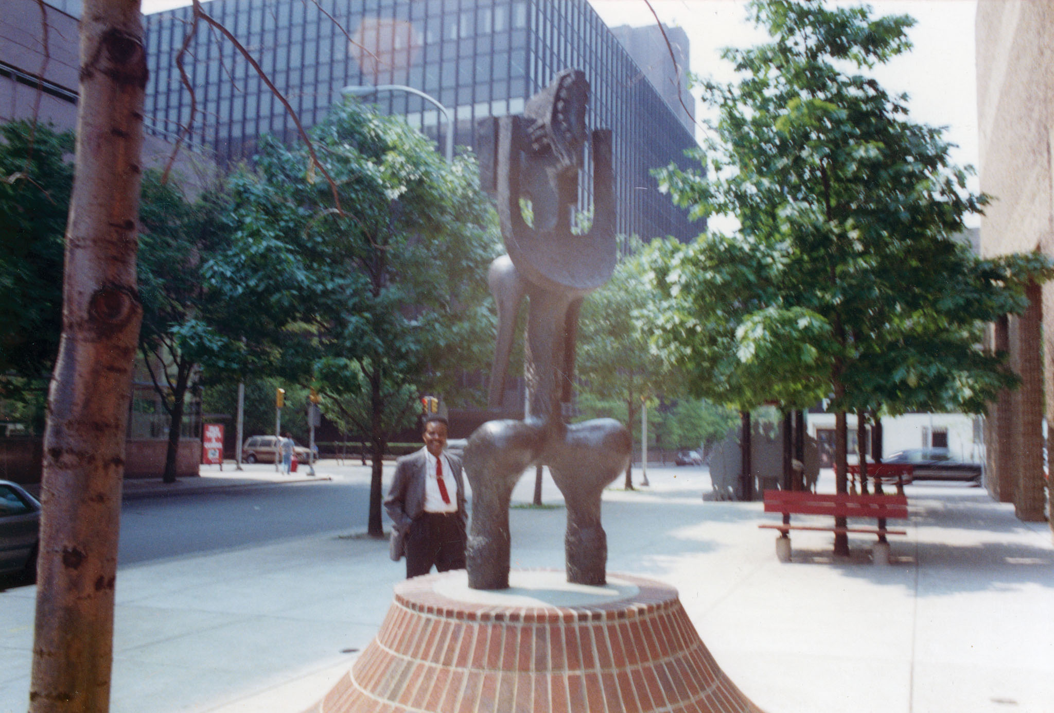 A person stands behind a sculpture mounted to a brink base.