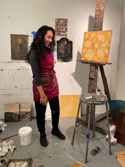 Júlia Godoy stands in front of easel in art studio