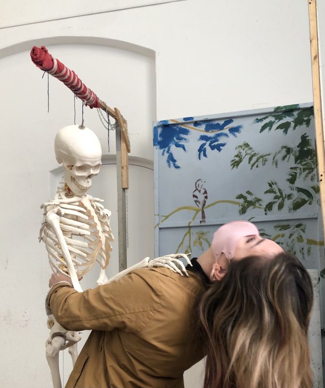 BFA student Faith Castillo leans backwards while holding a skeleton model