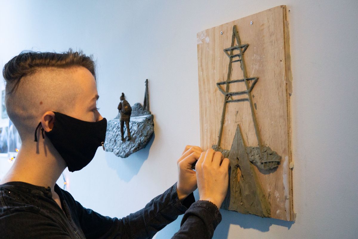 Varvàra Fern in mask adjusting art work on wall
