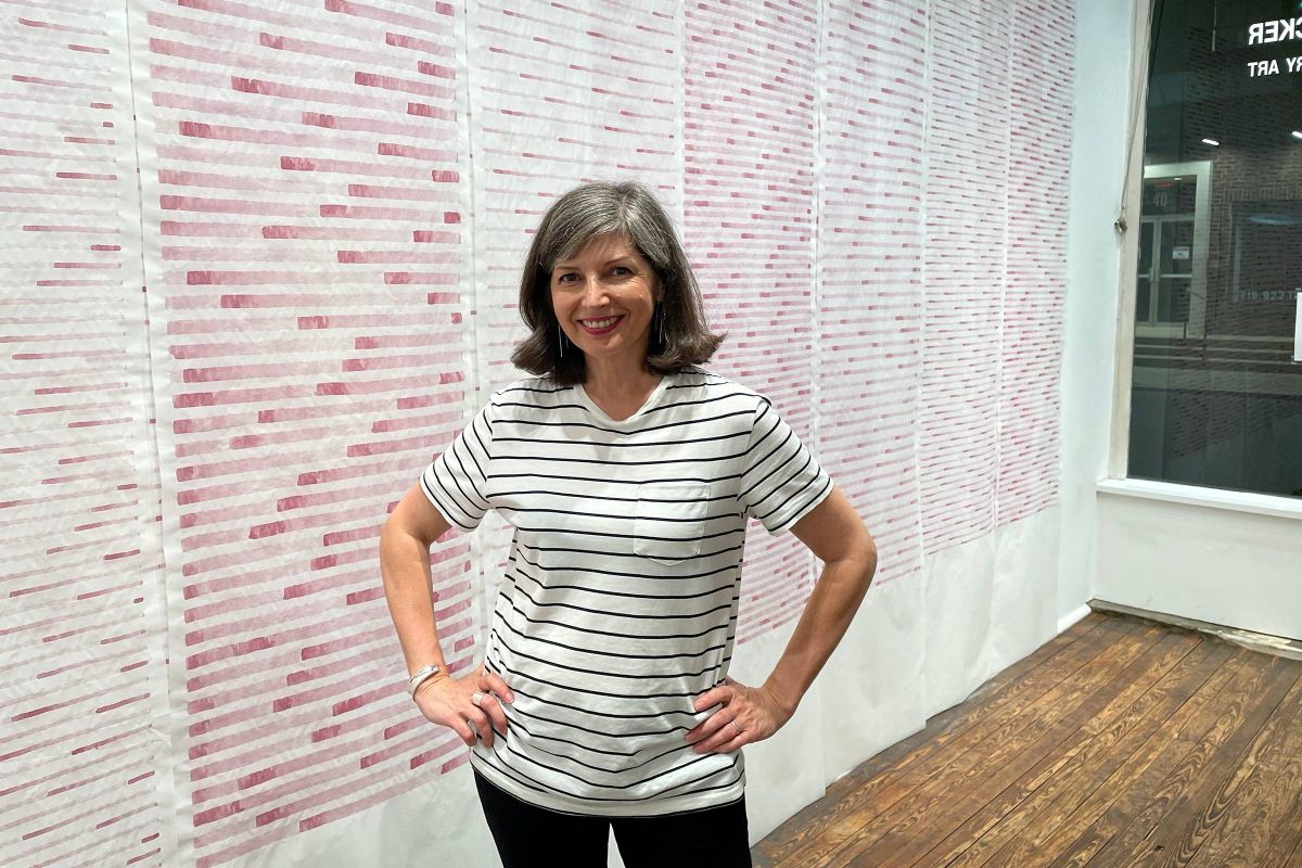 Anna Bogatin Ott standing in front of her red wine drawings.