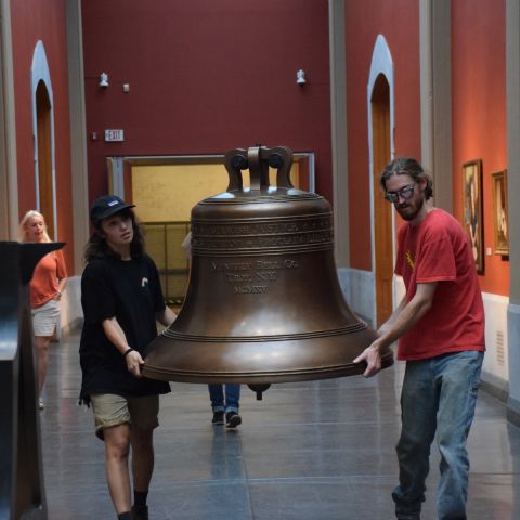 Alumni Erin Addie '18 and Gary Pergolini '18 move the replica Justice Bell into the Rotunda of the Historic Landmark Building.