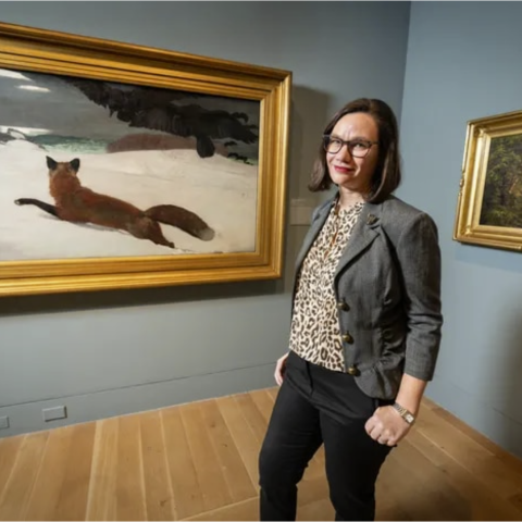 Anna Marley standing in front of landscape painting with fox in snow and crows above