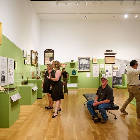 People standing in a gallery featuring historic objects on display.