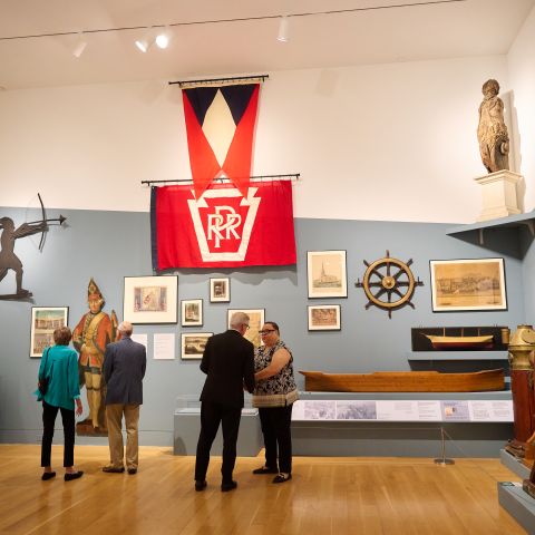 People standing in a gallery featuring historic objects on display.