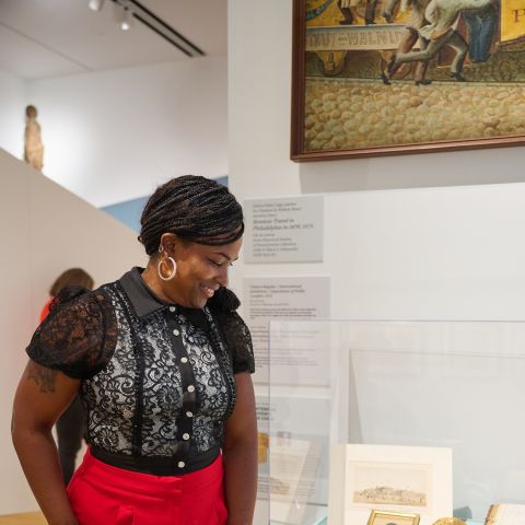 a woman looks down at a display case