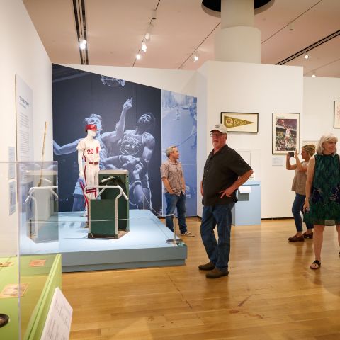 People standing in a gallery featuring historic objects on display.