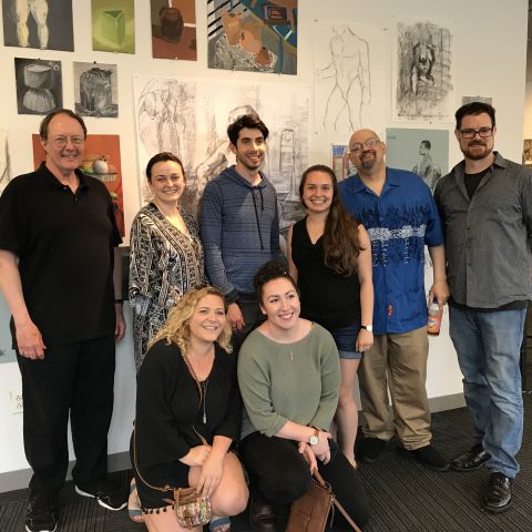 Al Gury posing with a group of students with artwork in the background