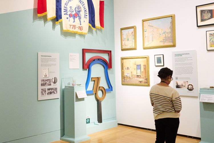 A person standing in a gallery looking at an item in a display case.